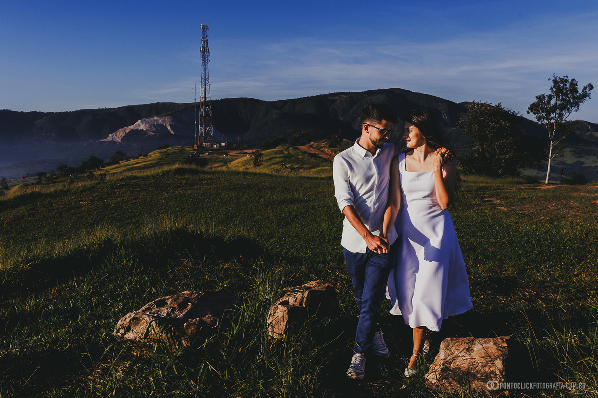 Casal caminhando no Morro do Capuava em Pirapora do Bom Jesus durante ensaio pré wedding com montanhas ao fundo e luz suave do amanhecer criando cenário natural amplo