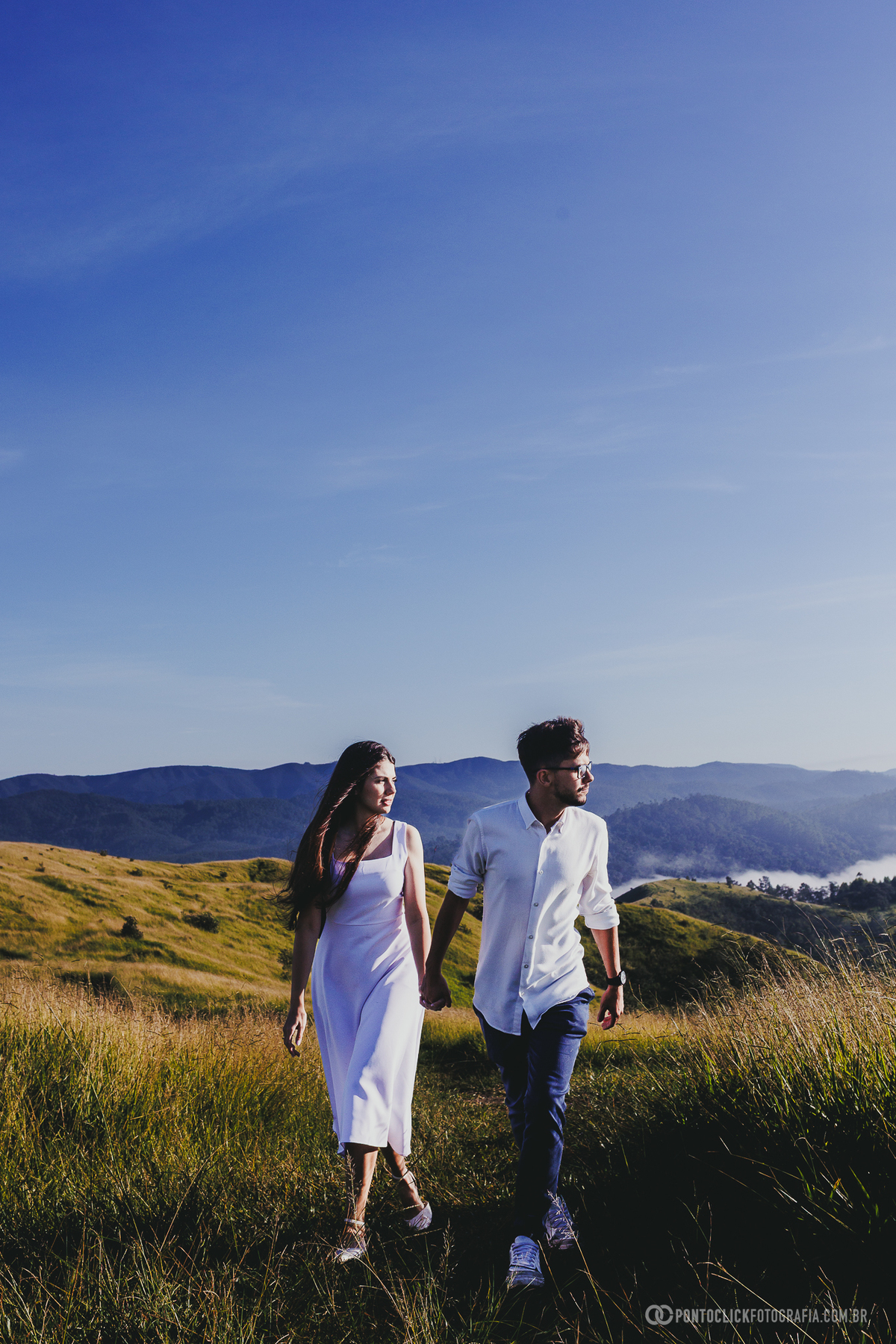 Casal em ensaio pré wedding no Morro do Capuava em Pirapora do Bom Jesus em pose lateral com luz suave e bandeira ao centro criando composição minimalista e elegante