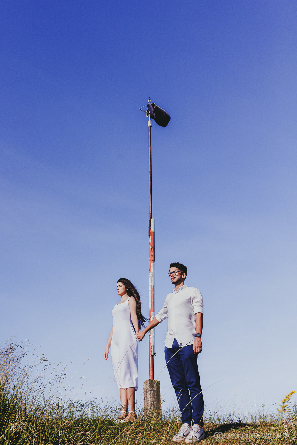 Casal em ensaio pré wedding no Morro do Capuava em Pirapora do Bom Jesus em momento de proximidade com montanhas ao fundo e luz lateral criando atmosfera romântica
