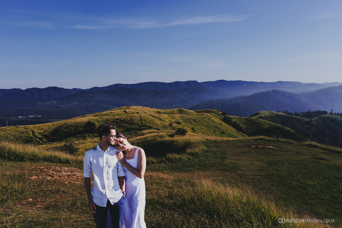 Casal em ensaio pré wedding no Morro do Capuava em Pirapora do Bom Jesus com mãos desfocadas em primeiro plano criando composição criativa com profundidade