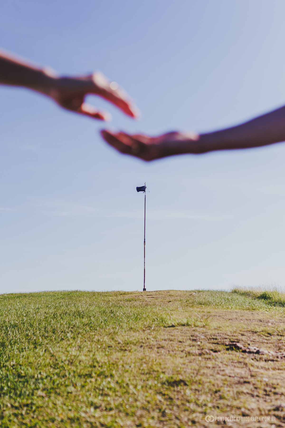 Casal em ensaio pré wedding no Morro do Capuava em Pirapora do Bom Jesus com mãos desfocadas em primeiro plano criando composição criativa com profundidade