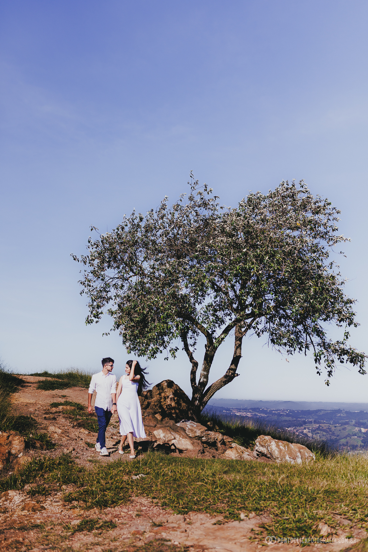 Paisagem no Morro do Capuava em Pirapora do Bom Jesus com árvore isolada e casal ao fundo criando cenário natural amplo com luz suave e composição equilibrada