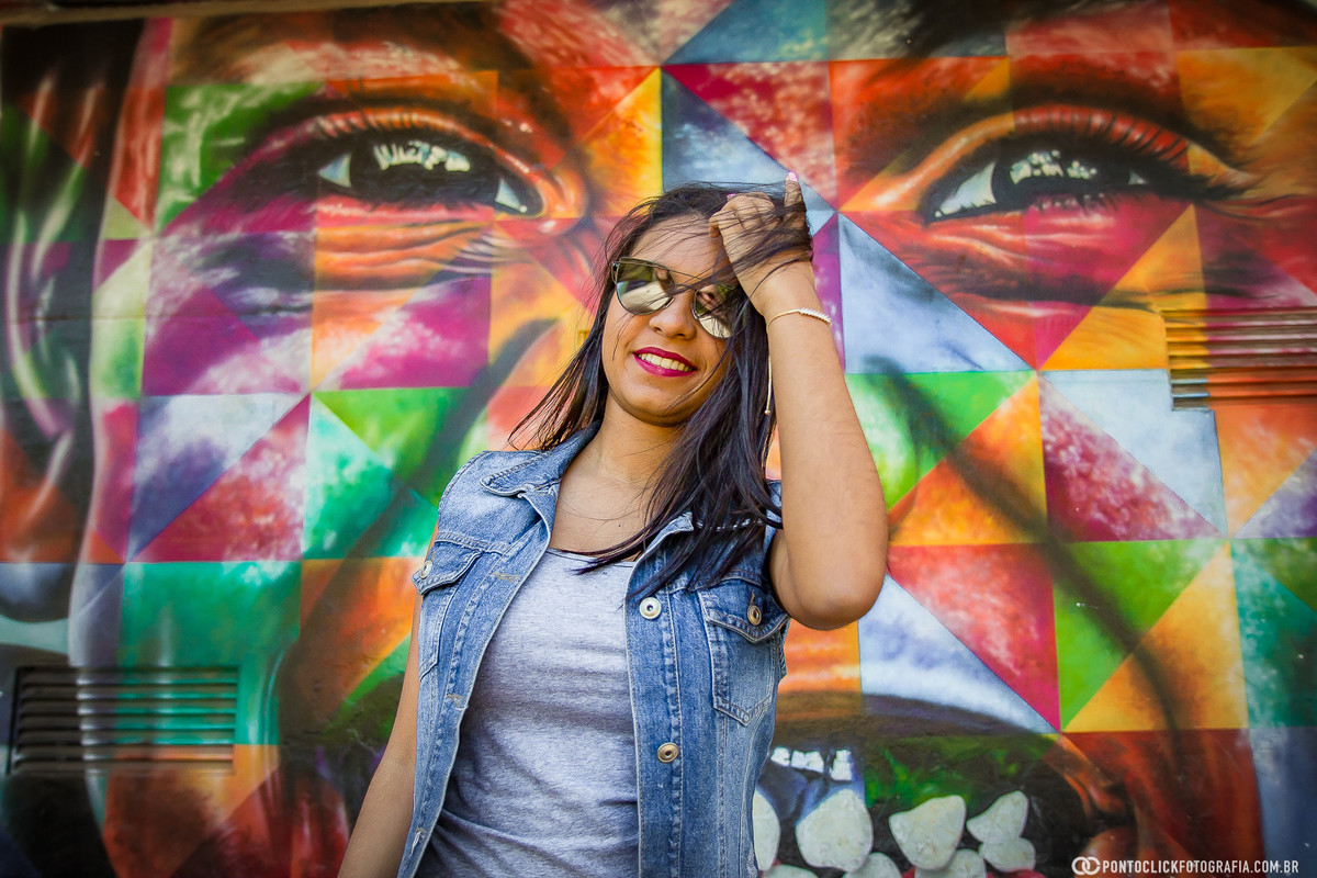 com a mão no cabelo encostada na linda pintura do parque ibirapuera