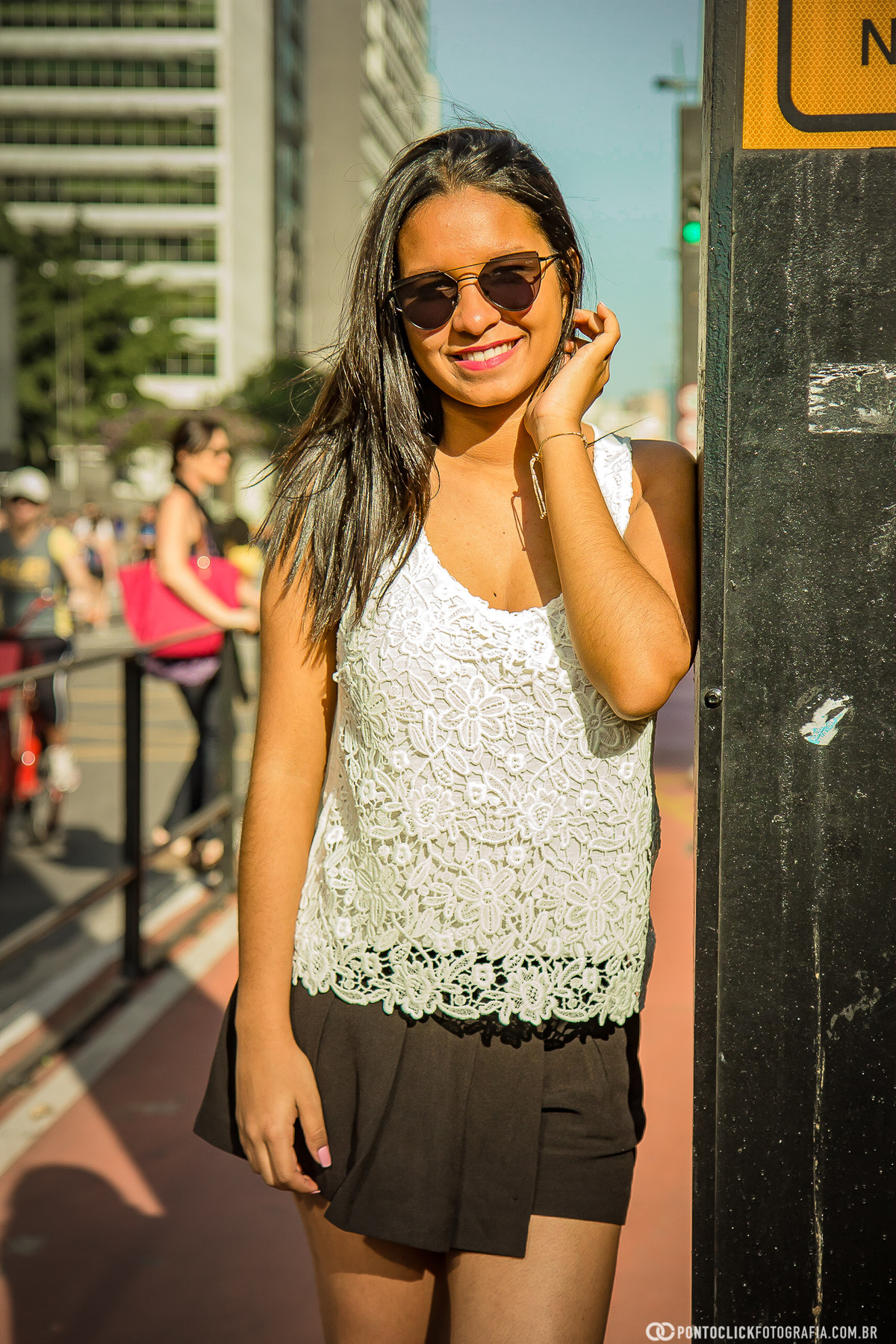 sorrindo e com a mão no pescoço na avenida paulista