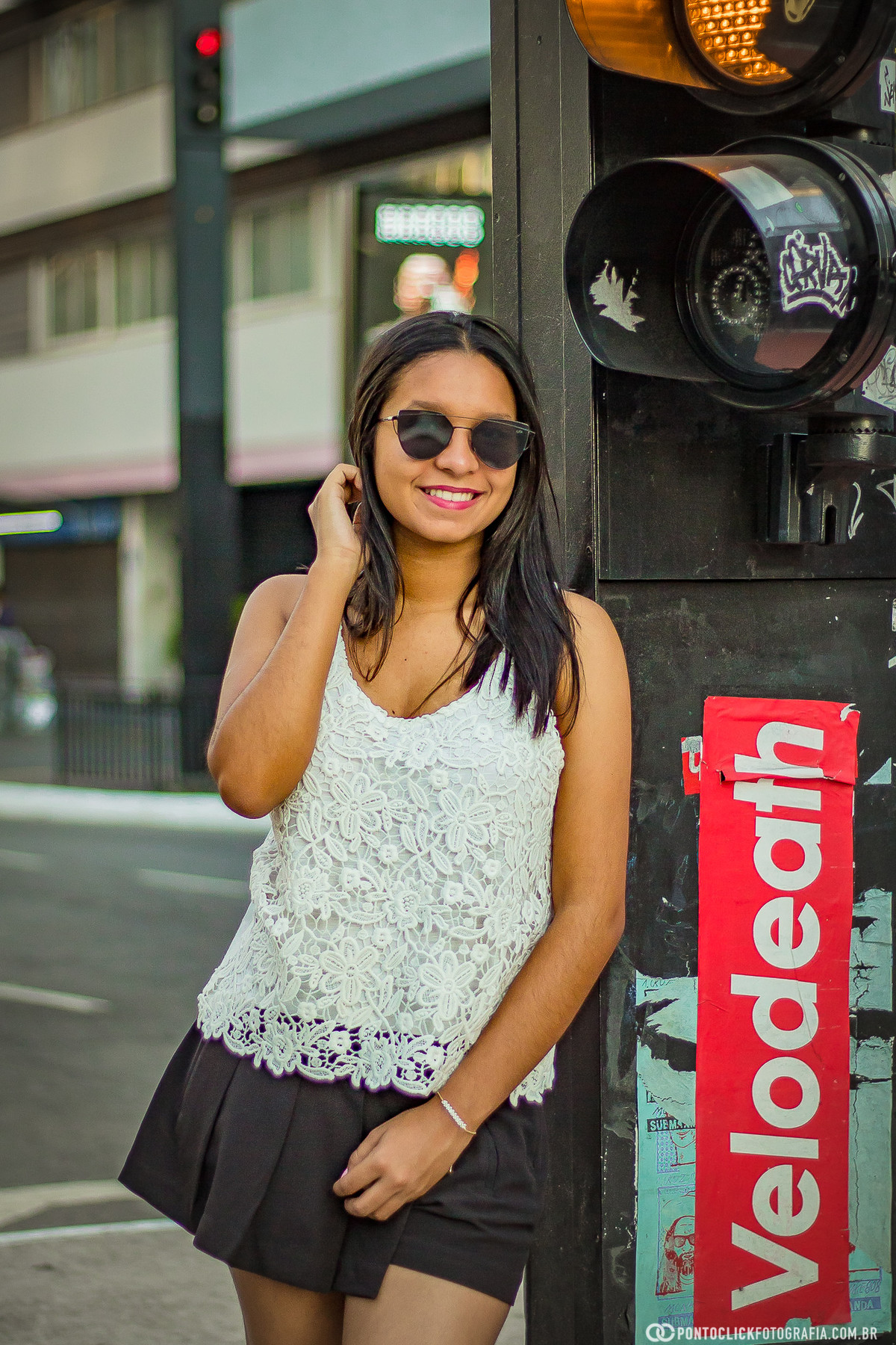 com a mão no cabelo e encostada no farol da avenida paulista