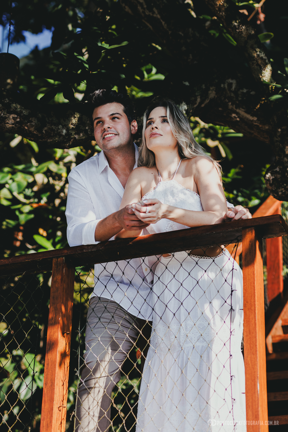 Fotografia de casal realizada no Guarujá com Guilherme e Katioska em clima romântico próximo ao mar e às pedras da praia, valorizando luz natural e conexão espontânea do casal