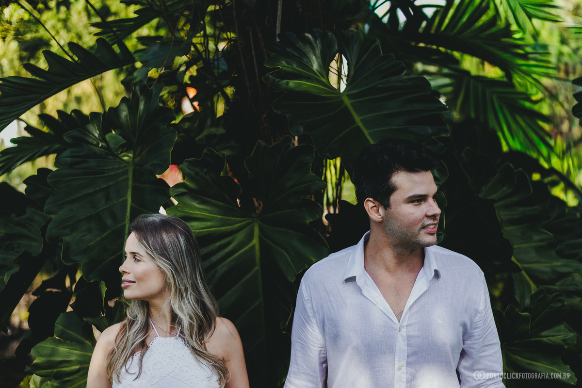 Ensaio pre wedding de Guilherme e Katioska no litoral paulista com cenário tropical e folhas naturais ao fundo, registrando conexão, romantismo e leveza do casal durante sessão fotográfica no Guarujá