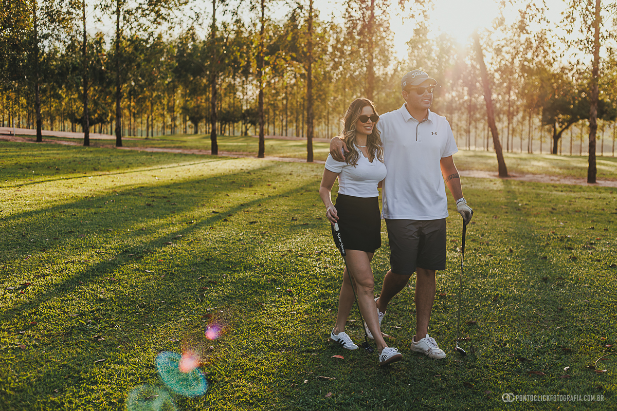 Casal caminha lado a lado durante ensaio fotográfico em campo de golfe, registrando momentos leves e espontâneos. A fotografia combina natureza, esporte e romantismo em um cenário perfeito para ensaio lifestyle