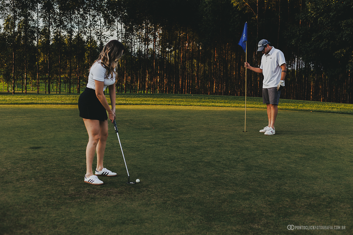 Participante realiza uma tacada no green durante ensaio fotográfico em campo de golfe. A fotografia combina esporte, natureza e elegância, criando imagens autênticas em um ambiente sofisticado ao ar livre