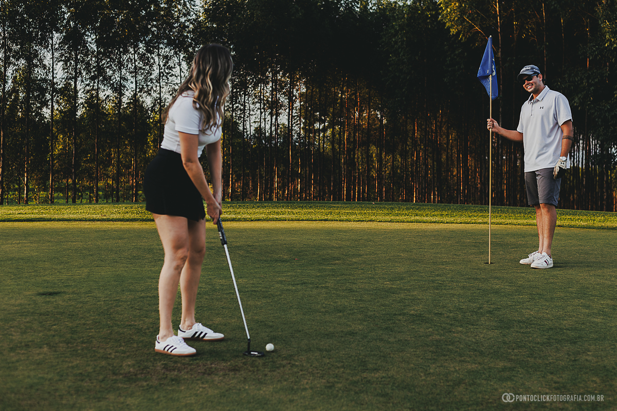 Casal vive momentos descontraídos durante ensaio fotográfico no green de um campo de golfe. A fotografia evidencia cumplicidade, diversão e um cenário diferenciado para registrar lembranças com luz natural