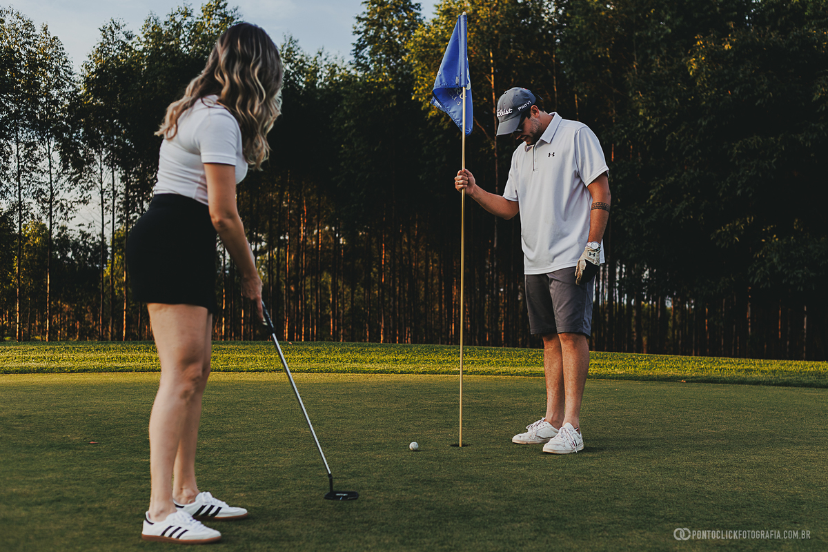 Casal participa de uma experiência de golfe durante ensaio fotográfico lifestyle, explorando diferentes momentos no green. A fotografia destaca naturalidade, elegância e a beleza de um cenário ao ar livre