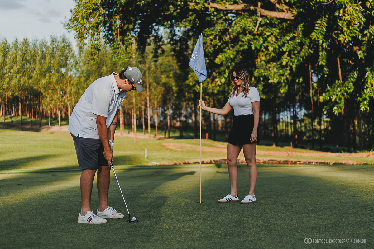 Casal participa de ensaio fotográfico no green de um campo de golfe, explorando diferentes poses e momentos espontâneos. A fotografia une esporte, natureza e romantismo em um cenário elegante para registrar boas lembranças