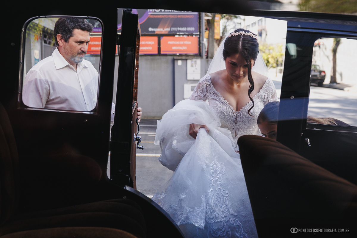 A noiva entra no carro antigo que a levará até a cerimônia, vivendo um dos momentos mais marcantes do casamento. Fotógrafo de casamento Pontoclick Fotografia.
