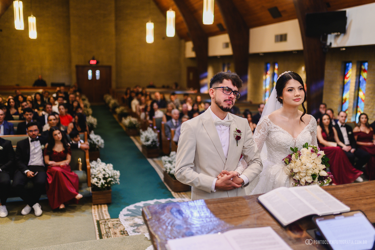 Os noivos permanecem diante do altar durante a cerimônia religiosa, celebrando a união em um momento repleto de significado e emoção. Fotógrafo de casamento Pontoclick Fotografia.