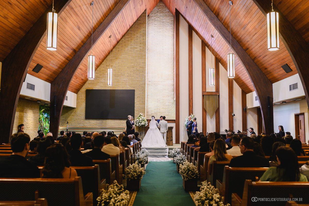 Vista ampla da cerimônia de casamento mostrando os noivos diante do altar e todos os convidados reunidos para celebrar esse momento inesquecível. Fotógrafo de casamento Pontoclick Fotografia.
