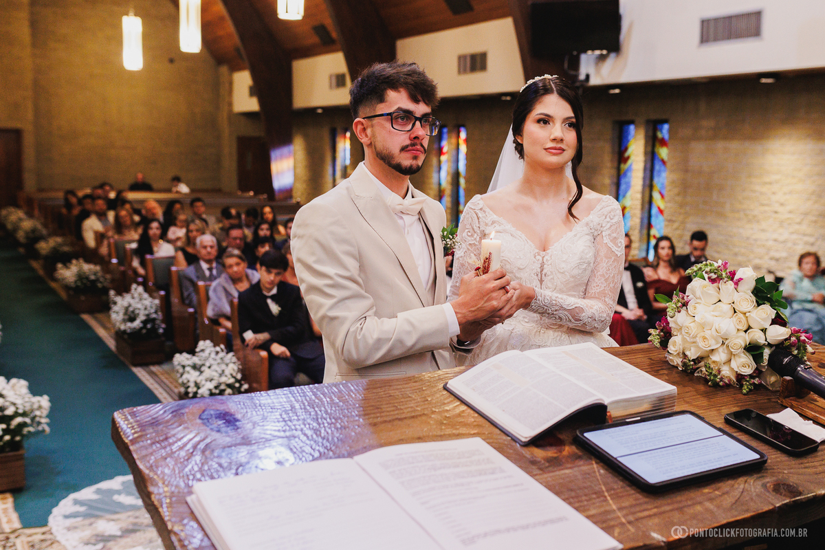 O casal participa de um momento simbólico durante a cerimônia de casamento, representando a união e o compromisso celebrado diante dos convidados. Fotógrafo de casamento Pontoclick Fotografia.