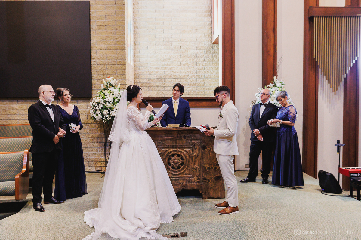 Os noivos trocam palavras diante do altar durante a cerimônia religiosa, vivendo um dos momentos mais importantes da celebração do casamento. Fotógrafo de casamento Pontoclick Fotografia.