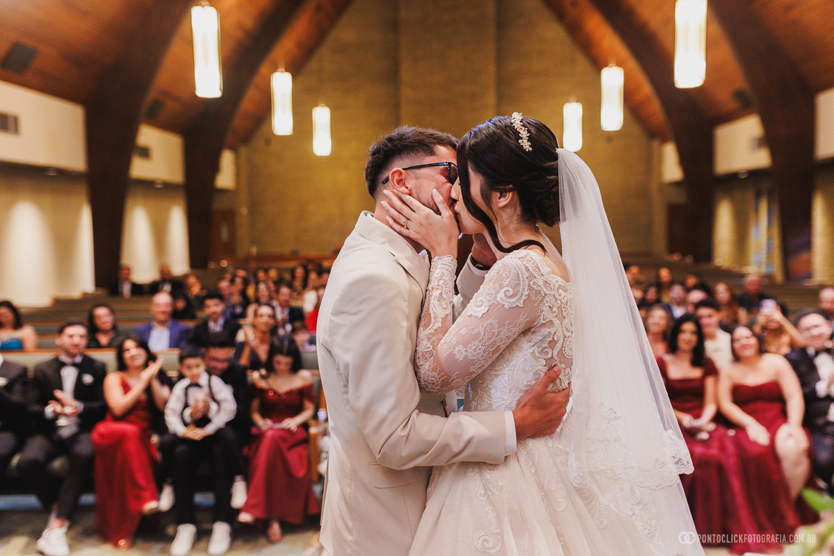 Os noivos celebram o primeiro beijo como casados diante dos convidados, registrando um dos momentos mais marcantes e emocionantes da cerimônia de casamento. Fotógrafo de casamento Pontoclick Fotografia.