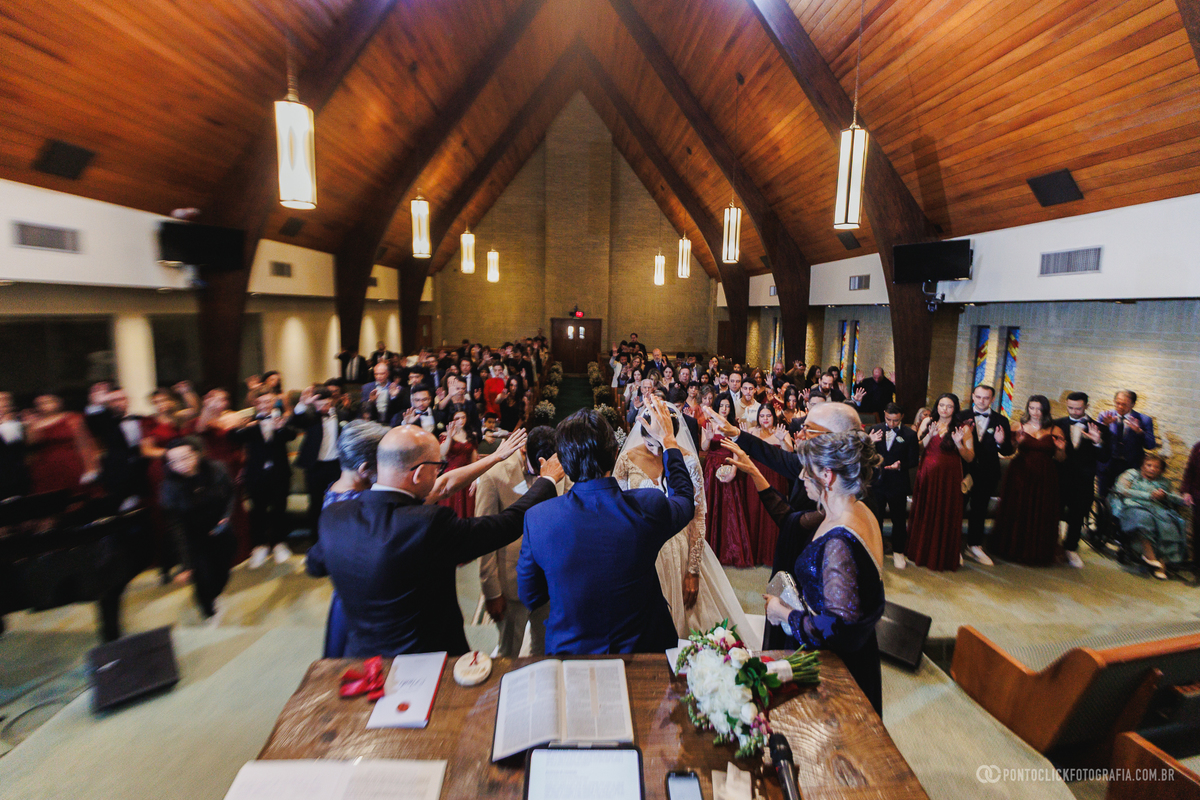 Familiares e convidados estendem as mãos em oração pelos noivos durante a cerimônia, tornando a celebração ainda mais emocionante e especial. Fotógrafo de casamento Pontoclick Fotografia.