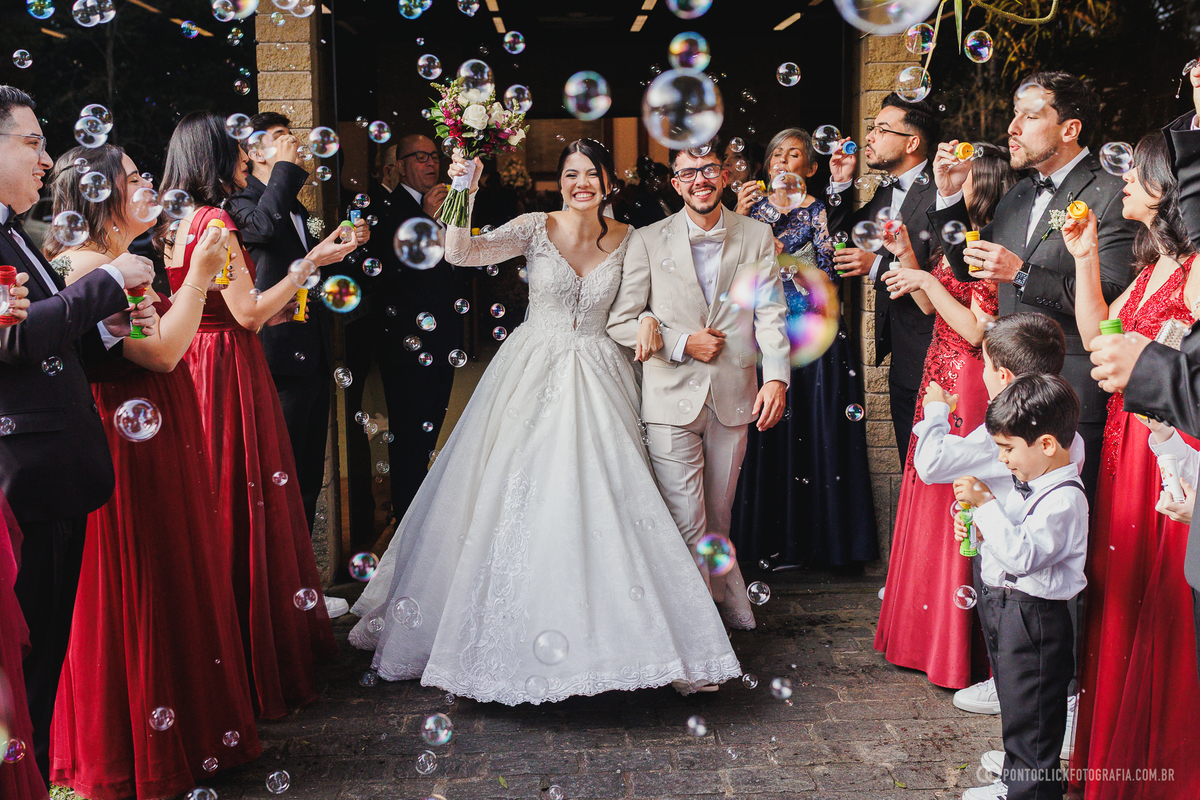 A saída dos noivos é celebrada pelos convidados com bolhas de sabão, criando um cenário leve, alegre e inesquecível para o casamento. Fotógrafo de casamento Pontoclick Fotografia.