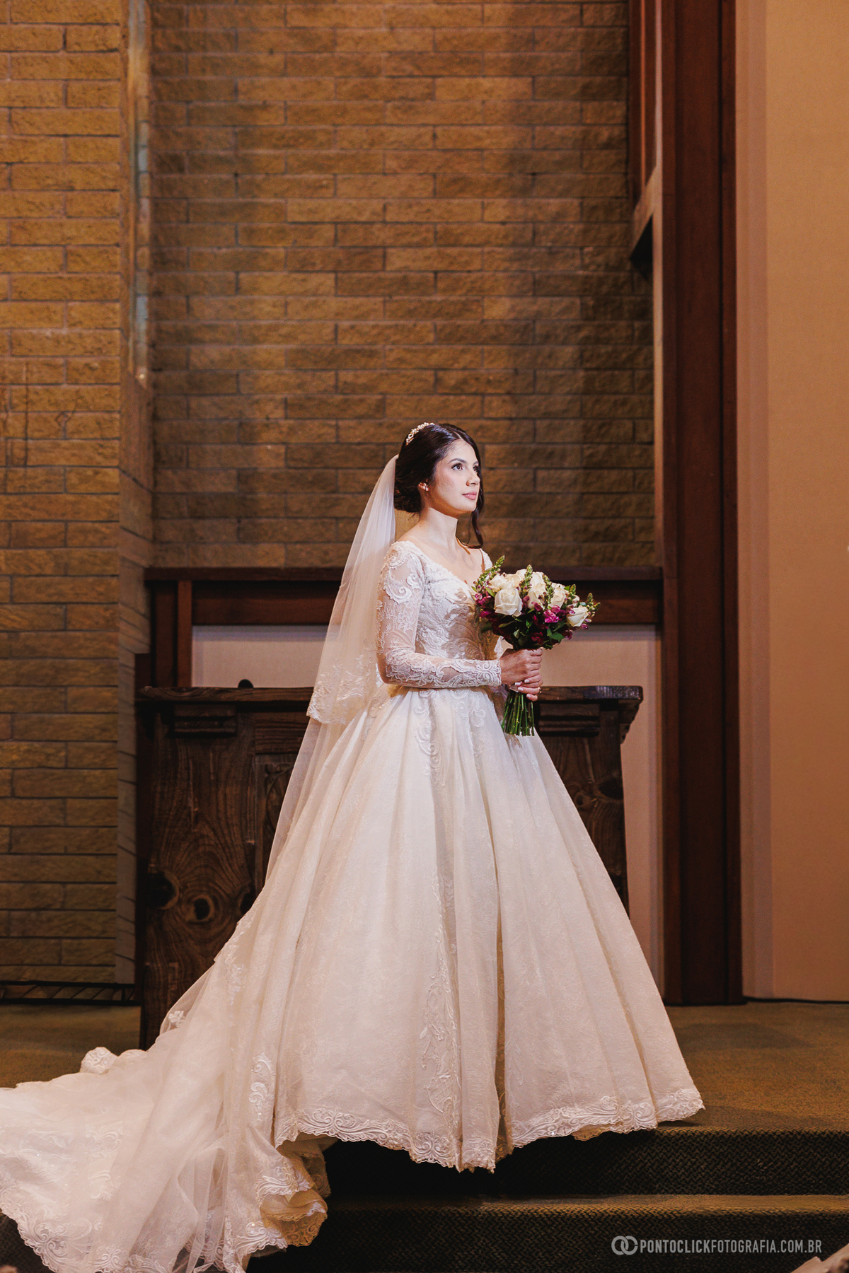 A noiva posa com seu buquê diante do altar após a cerimônia, valorizando os detalhes do vestido e a elegância desse dia inesquecível. Fotógrafo de casamento Pontoclick Fotografia.