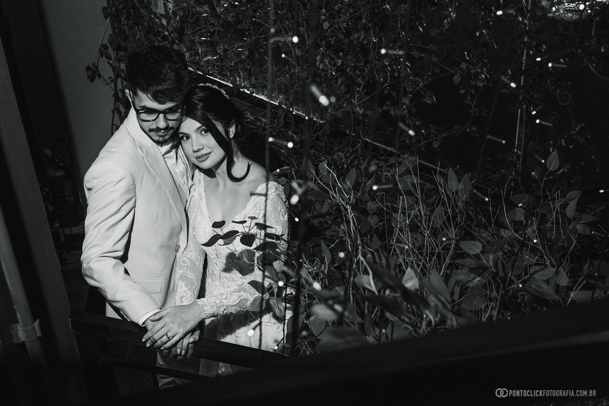Em um retrato em preto e branco, os noivos aparecem abraçados em um ambiente iluminado, destacando a conexão e a elegância do casal. Fotógrafo de casamento Pontoclick Fotografia.