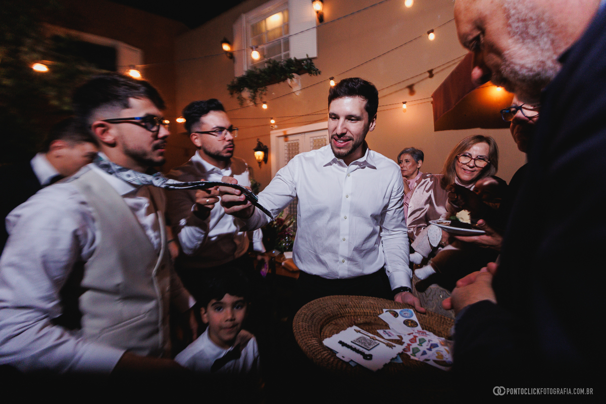 O noivo participa de uma brincadeira divertida durante a festa de casamento, cercado por familiares e amigos em um momento descontraído e cheio de risadas. Fotógrafo de casamento Pontoclick Fotografia.