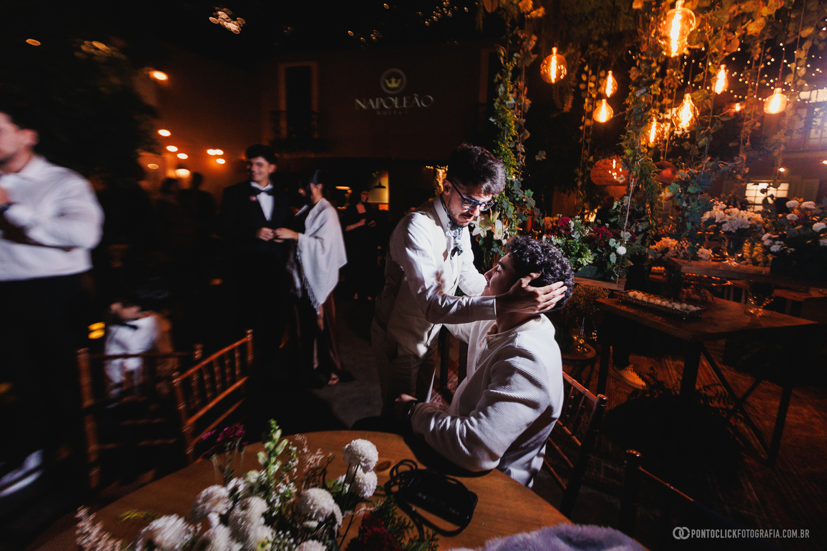 O noivo recebe um gesto de carinho e apoio de um amigo durante a recepção, registrando uma amizade verdadeira em meio à celebração do casamento. Fotógrafo de casamento Pontoclick Fotografia.