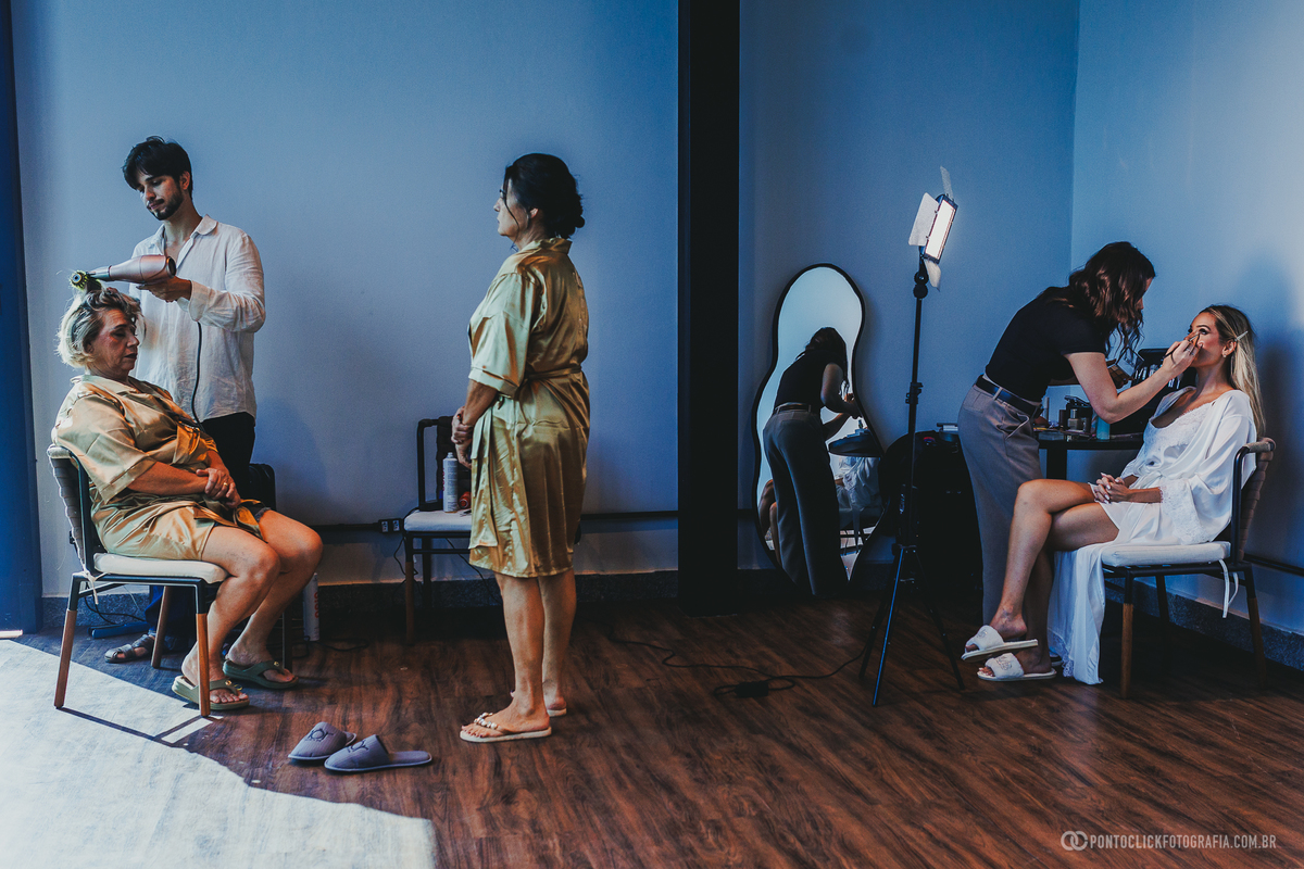 Profissionais de beleza cuidam do cabelo e da maquiagem de duas mulheres durante os preparativos do casamento. Fotógrafo de casamento Pontoclick Fotografia.