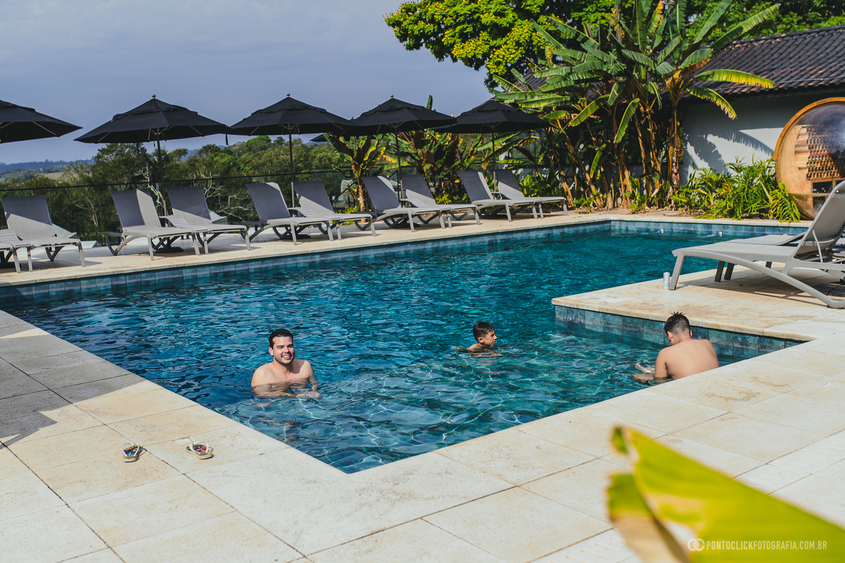 Homens aproveitam a piscina em um momento de descontração durante o dia do casamento. Fotógrafo de casamento Pontoclick Fotografia