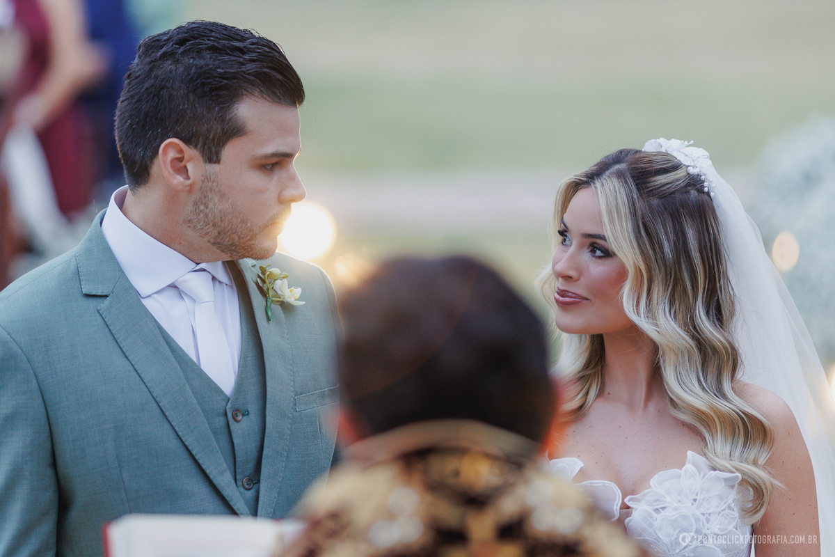 Os noivos trocam olhares durante a cerimônia de casamento ao ar livre. Fotógrafo de casamento Pontoclick Fotografia