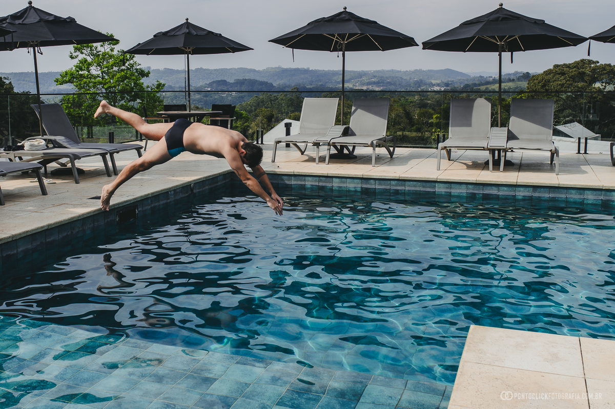 noivo mergulha na piscina, em uma cena espontânea registrada durante os preparativos do casamento. Fotógrafo de casamento Pontoclick Fotografia