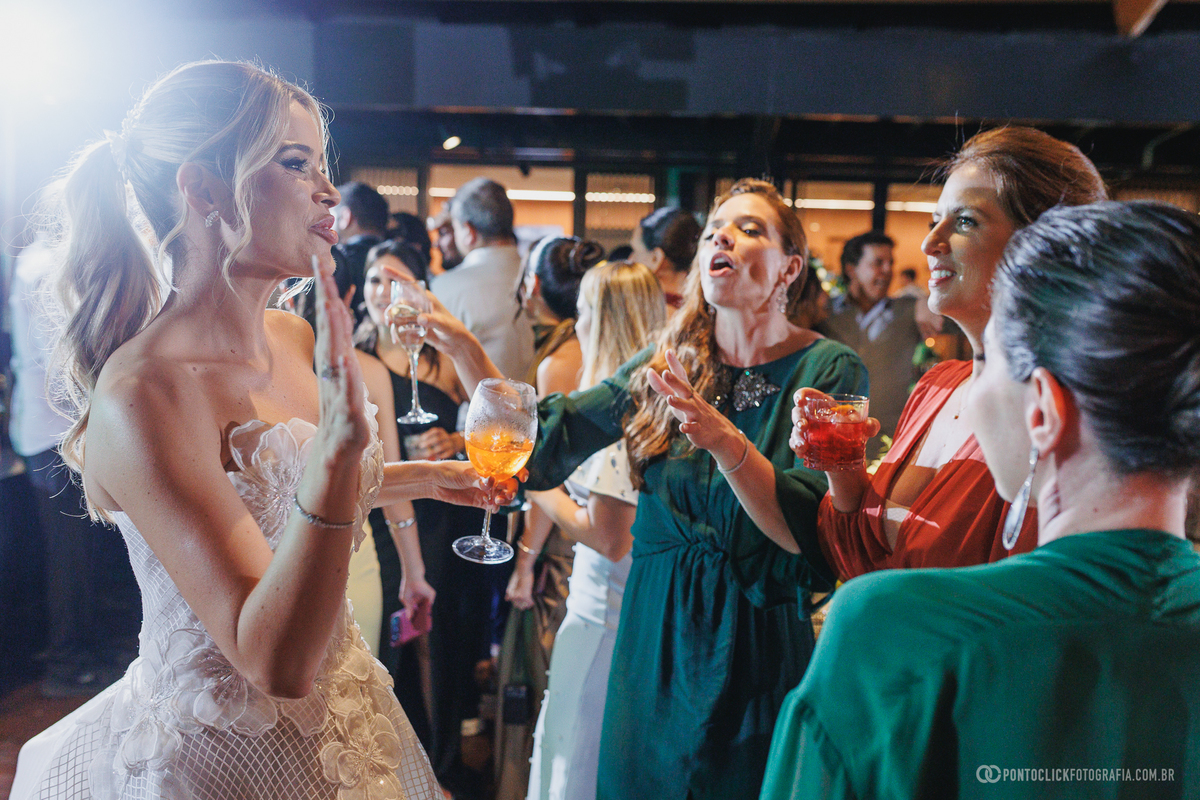 A noiva conversa e brinda com convidadas durante a recepção de casamento. Fotógrafo de casamento Pontoclick Fotografia.