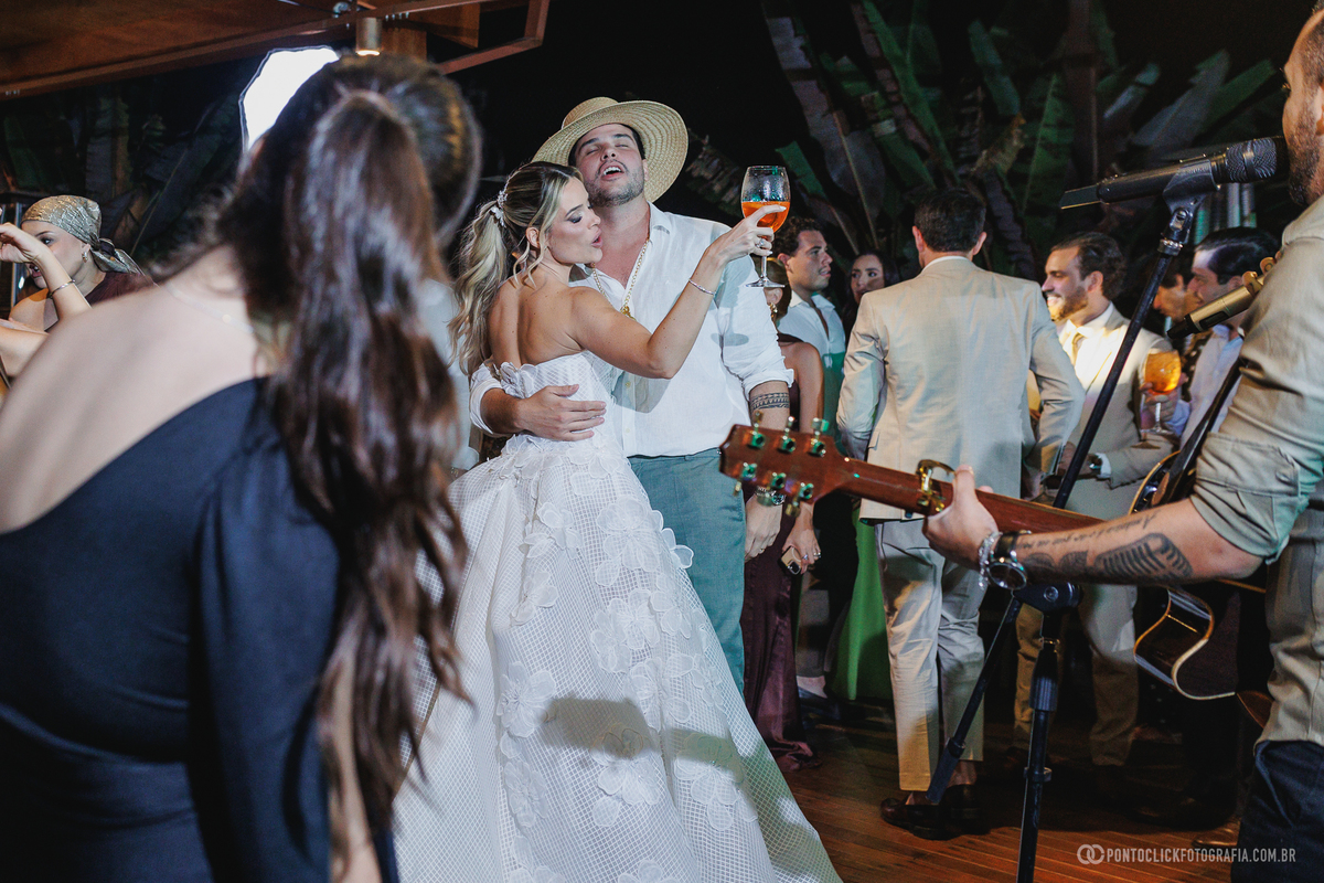A noiva dança com um convidado de chapéu durante a festa, perto dos músicos. Fotógrafo de casamento Pontoclick Fotografia.