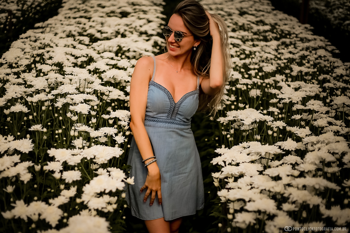 noiva com a mao no cabelo e sorrindo no meio da plantação de flores em holambra