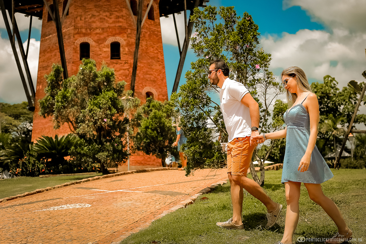 casal caminhando de mãos dadas no moinho de Holambra noivo esta mais na frente puxando a noiva
