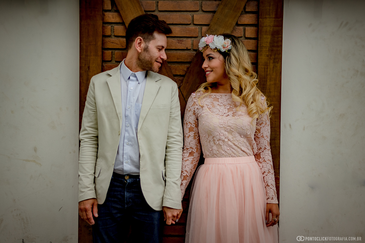 casal encostados na parede e olhando e sorrindo em campos do jordao