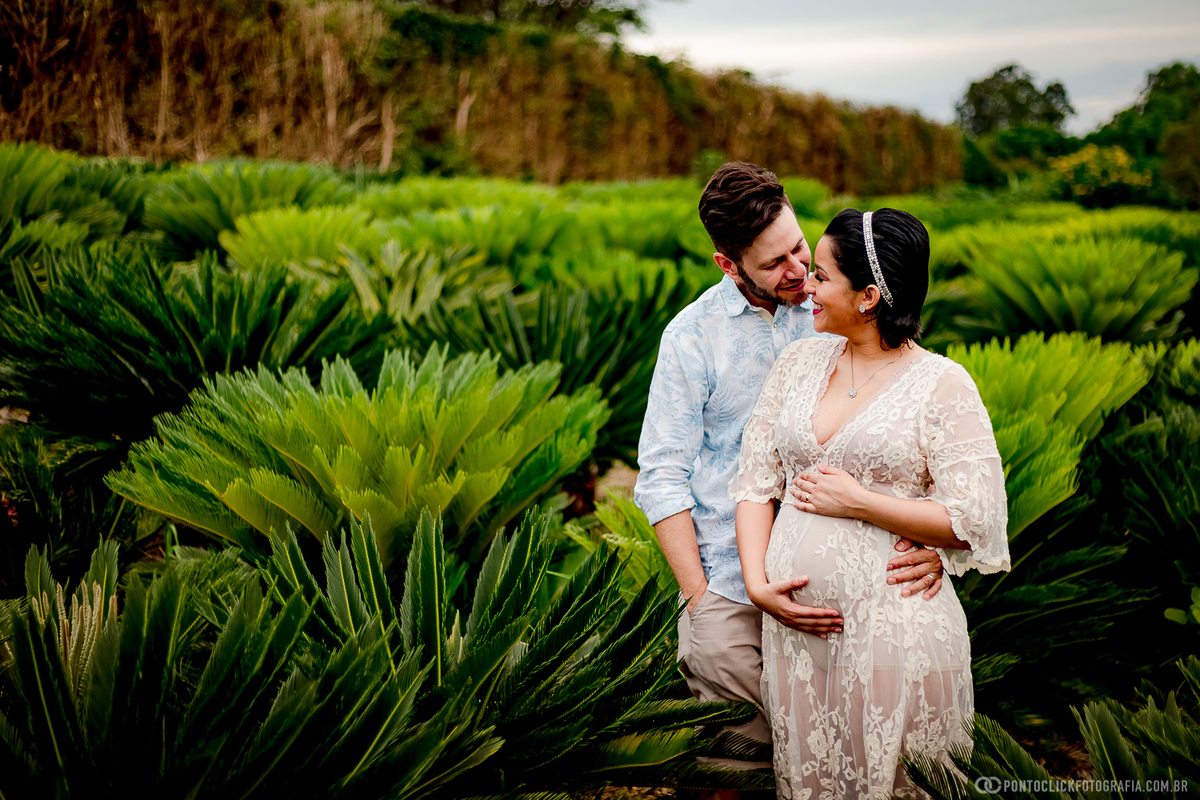 casal se olhando e gestante com as maos na barriga no meio da plantação de arvores em holambra cidade das flores