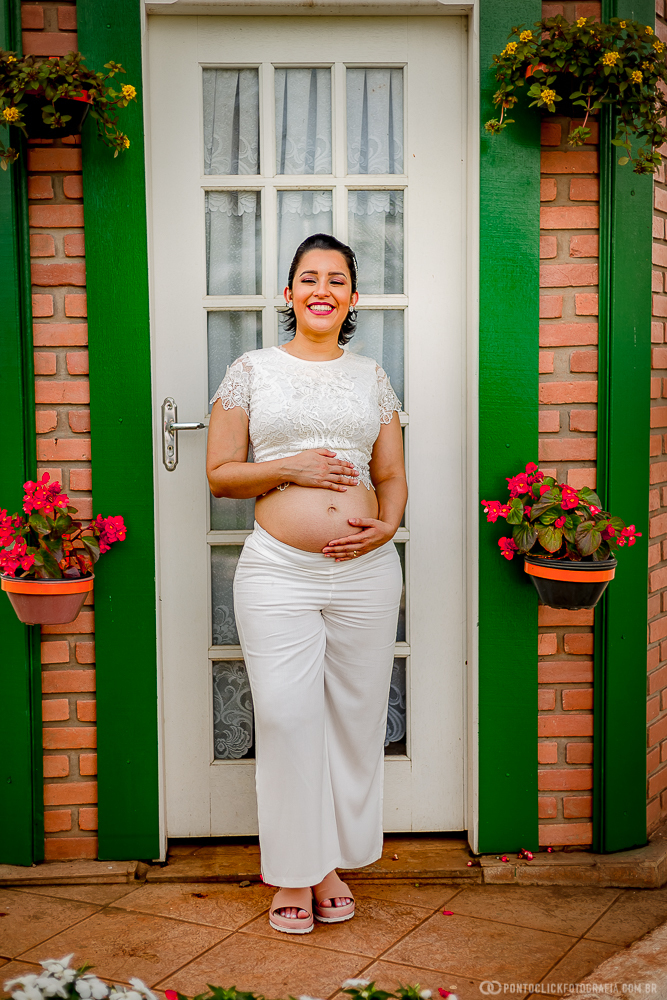 gestante com as maos na barriga na porta de uma casinha em holambra cidade das flores interior de sao paulo