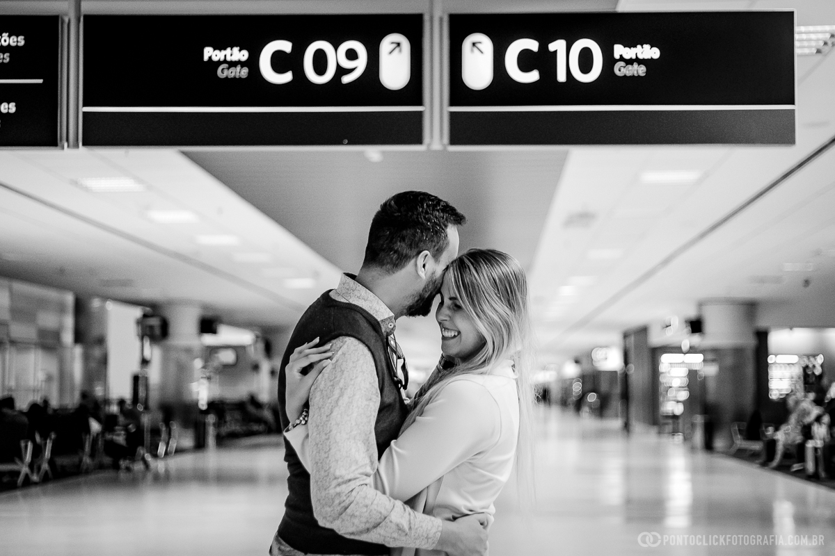 casal abraçados e a noiva sorrindo no meio do salao de embarque do aerporto de viracopos em ensaio fotografico no aeroporto
