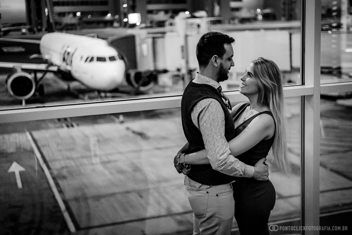casal abraçado e se olhando com um aviao no fundo no aeroporto viracopos  em ensaio fotografico no aeroporto