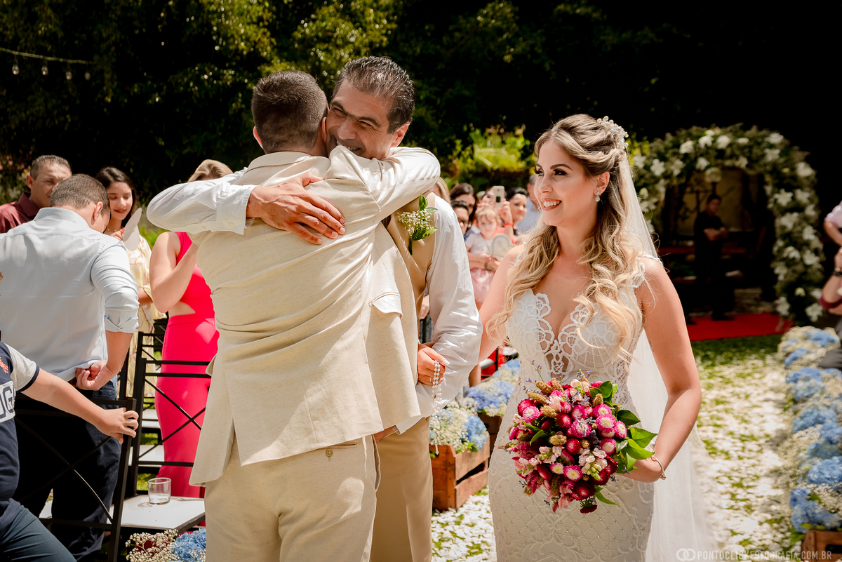 pai da noiva abraçando o noivo e noiva olhando para eles e sorrindo no laforet