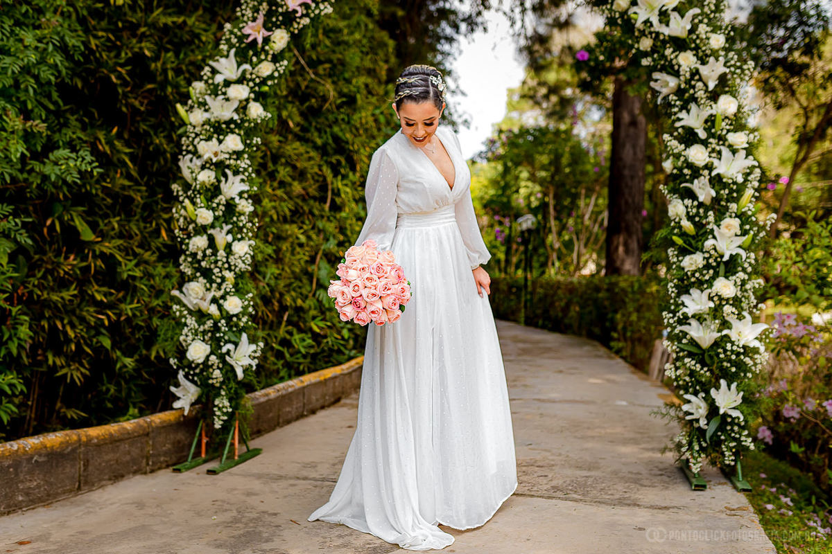 noiva olhando para a barra do seu vestido debaixo do arco de flores no Elopement Wedding no Espaço Laforet