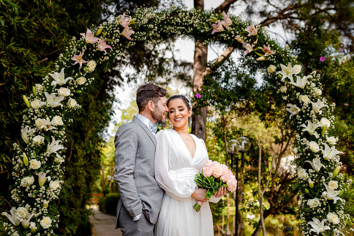 noica segurando o buquet de casamento e noivo com a mao no bolso e abraçando a noiva e beijando seu rosto no Elopement Wedding no Espaço Laforet