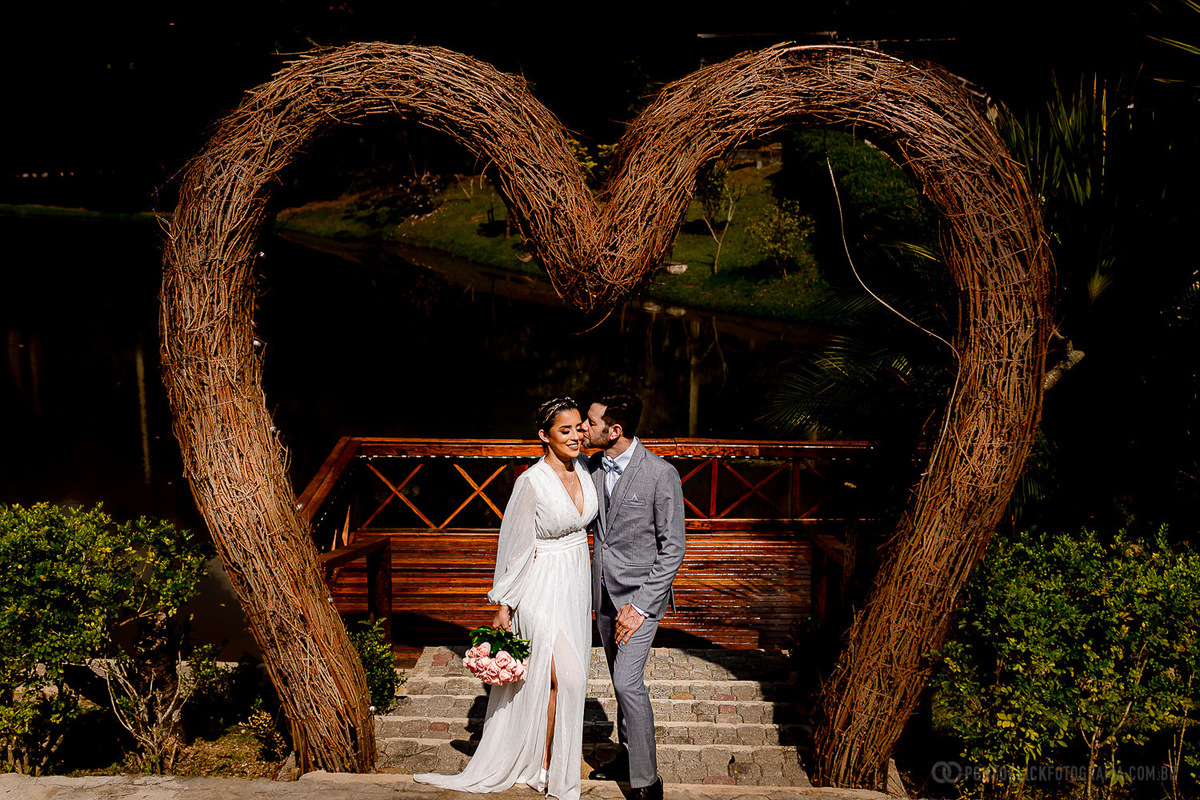 noivo beijando a noiva debaixo de um arco de coração feito de palha no Elopement Wedding no Espaço Laforet