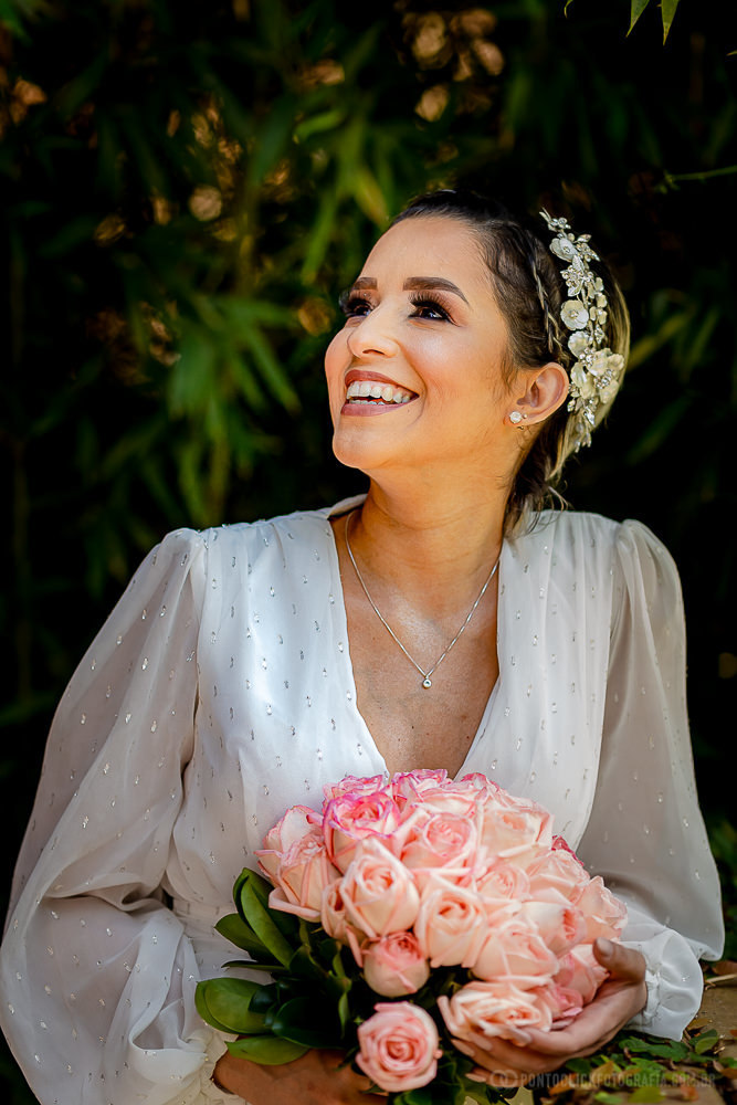 noiva sorrindo e olhando para o ceu segurando o buquet na frente do chale da novia no espaço laforet