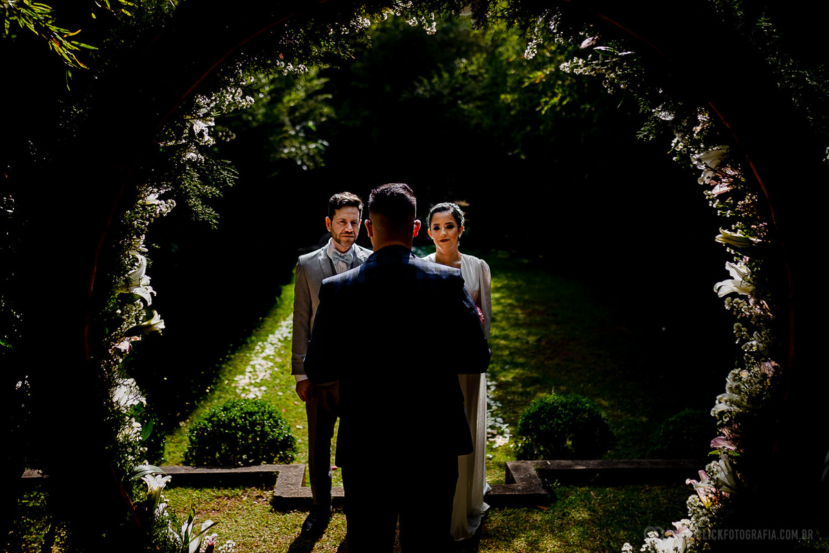 casal olhando para o celebrante  no meio de um arco de flores no Elopement Wedding no espaço laforet 