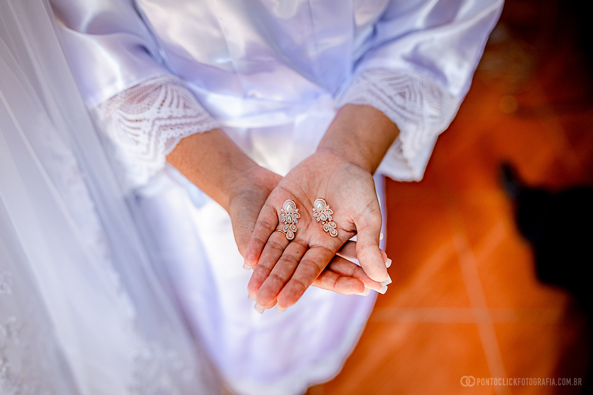 noiva segurando brincos na palma da mão