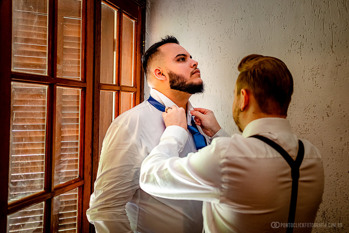padrinho ajustando a gravata do noivo
