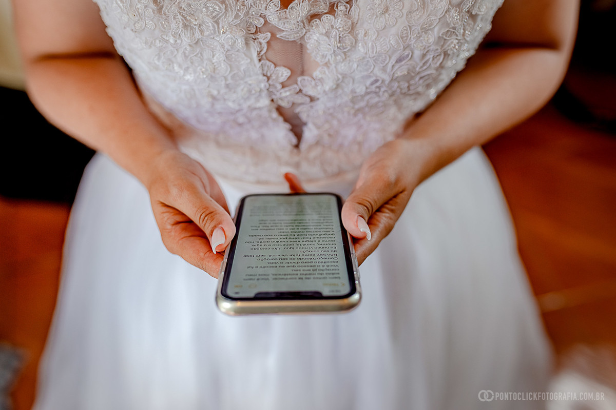 noiva vestida de branco segurando o celular com os votos de casamento